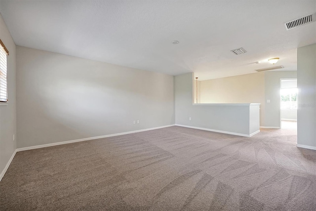 empty room with carpet floors, baseboards, and visible vents