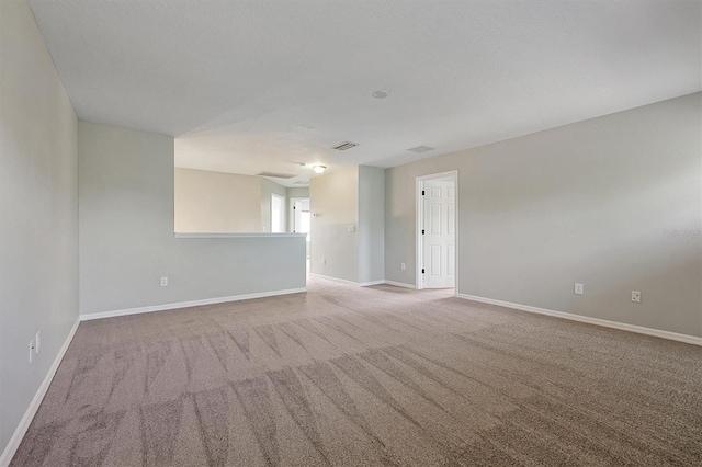 spare room featuring carpet flooring, baseboards, and visible vents