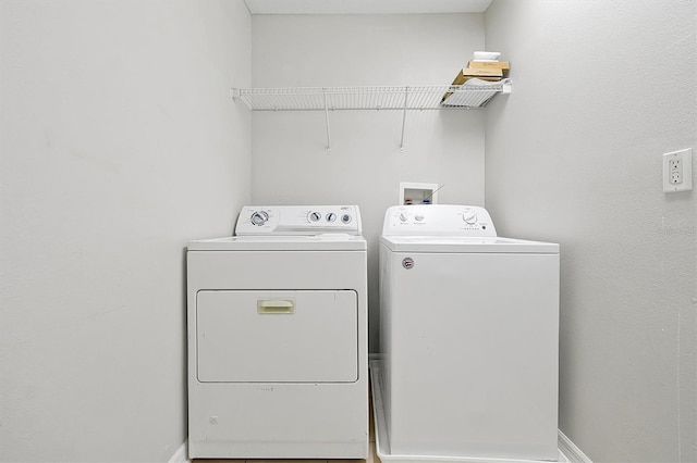 clothes washing area with laundry area, washing machine and dryer, and baseboards