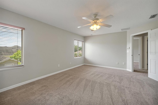spare room featuring visible vents, carpet flooring, baseboards, and a ceiling fan