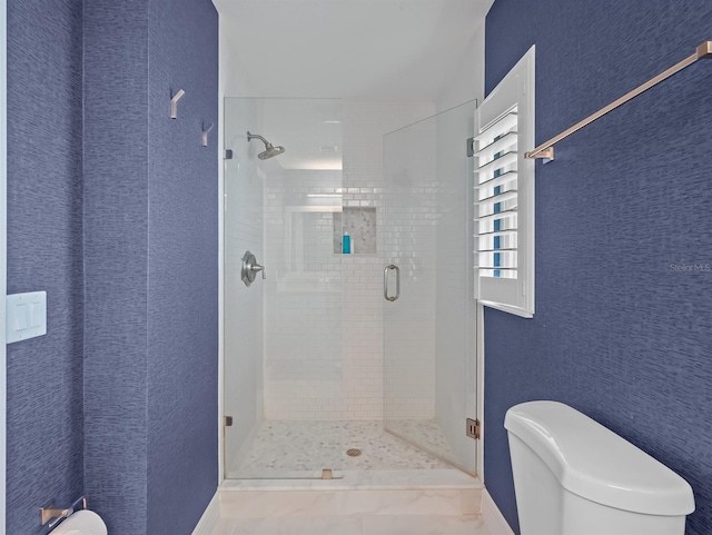 bathroom featuring a textured wall, toilet, and a stall shower