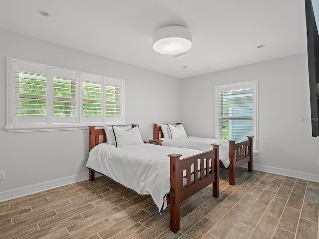 bedroom with baseboards, multiple windows, and wood tiled floor