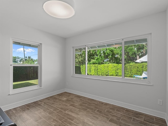 unfurnished room with wood tiled floor, baseboards, and a healthy amount of sunlight