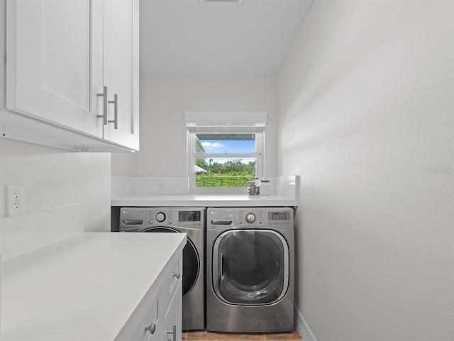 clothes washing area featuring baseboards, cabinet space, visible vents, and washer and clothes dryer