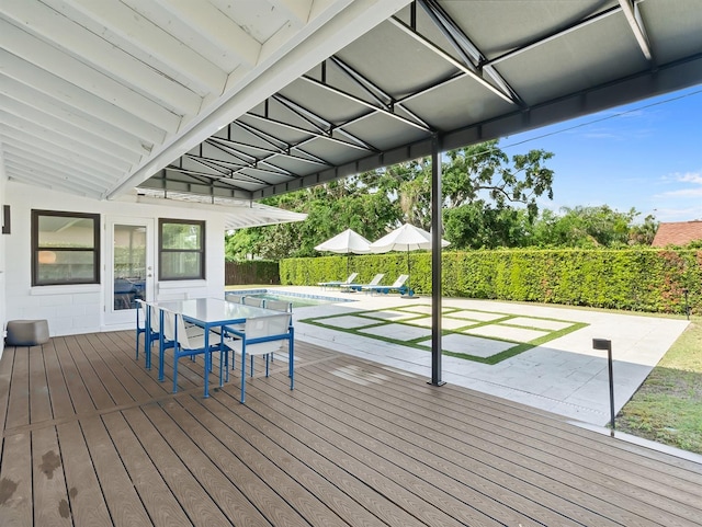deck featuring outdoor dining space, a fenced in pool, and a patio area