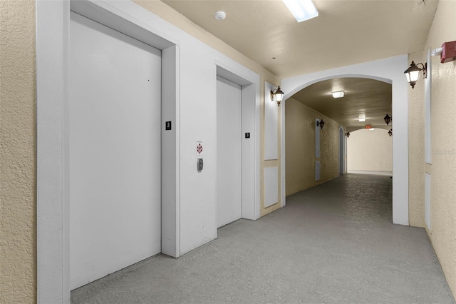 3314 Robert Trent Jones Dr Unit 308, Orlando, FL 32835 - corridor featuring elevator, arched walkways, finished concrete floors, and a textured wall