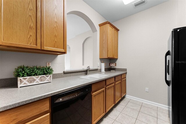 3314 Robert Trent Jones Dr Unit 308, Orlando, FL 32835 - kitchen featuring visible vents, light tile patterned floors, a sink, brown cabinetry, and black appliances