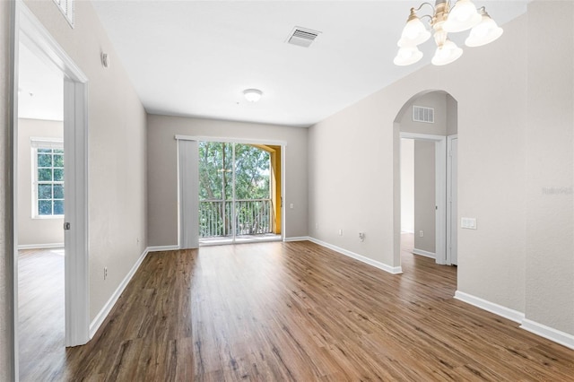3314 Robert Trent Jones Dr Unit 308, Orlando, FL 32835 - unfurnished room featuring a healthy amount of sunlight, arched walkways, a notable chandelier, and wood finished floors