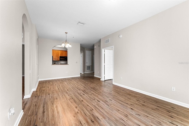3314 Robert Trent Jones Dr Unit 308, Orlando, FL 32835 - unfurnished living room featuring baseboards, a chandelier, light wood-style flooring, visible vents, and arched walkways