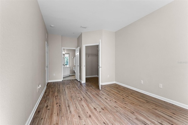 3314 Robert Trent Jones Dr Unit 308, Orlando, FL 32835 - unfurnished bedroom featuring a closet, baseboards, ensuite bathroom, a walk in closet, and light wood finished floors
