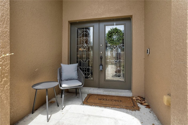 view of exterior entry with stucco siding and french doors