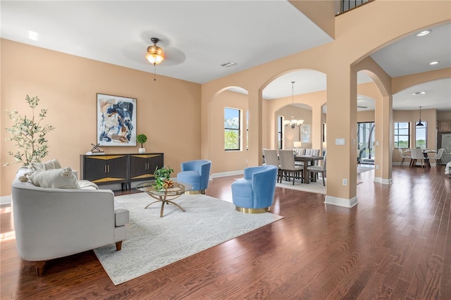 living room featuring wood finished floors, visible vents, baseboards, and arched walkways