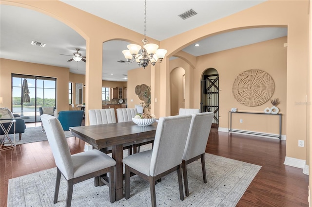 dining room featuring dark wood-type flooring, visible vents, baseboards, and arched walkways