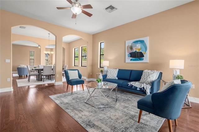 living area with arched walkways, visible vents, hardwood / wood-style flooring, and baseboards