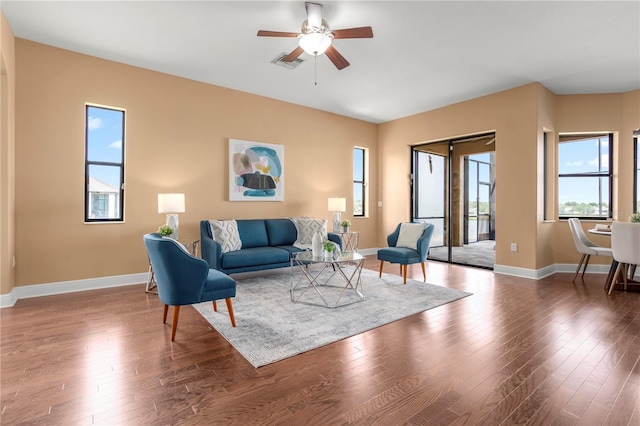 living room with a ceiling fan, visible vents, and baseboards