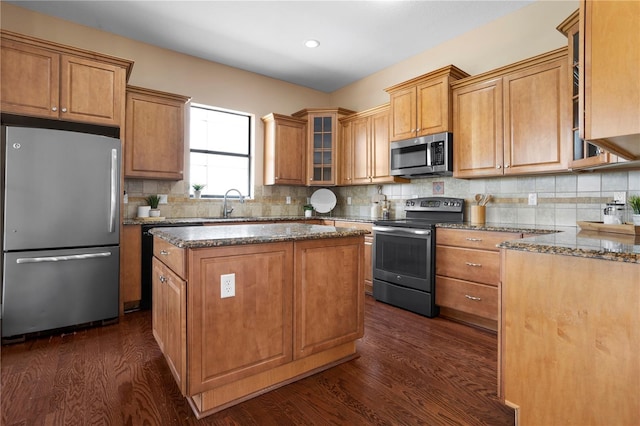 kitchen with dark stone countertops, dark wood-style flooring, stainless steel appliances, and a center island