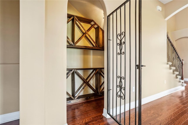 wine room featuring baseboards, wood finished floors, and arched walkways
