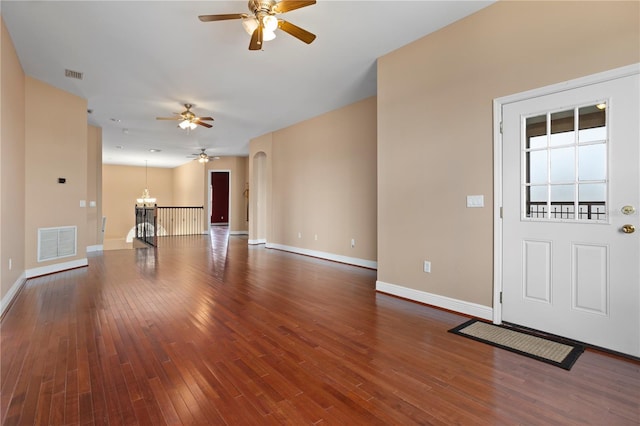 unfurnished living room with wood-type flooring, visible vents, baseboards, and ceiling fan with notable chandelier