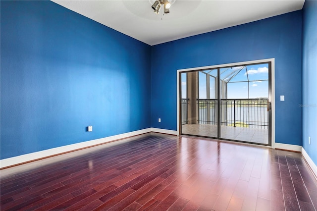 unfurnished room featuring wood finished floors, a ceiling fan, and baseboards