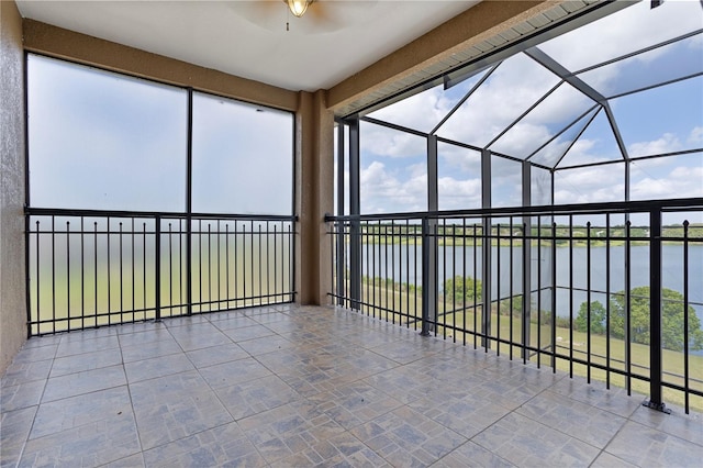 unfurnished sunroom featuring ceiling fan and a water view