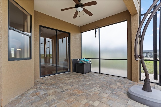 unfurnished sunroom featuring a ceiling fan