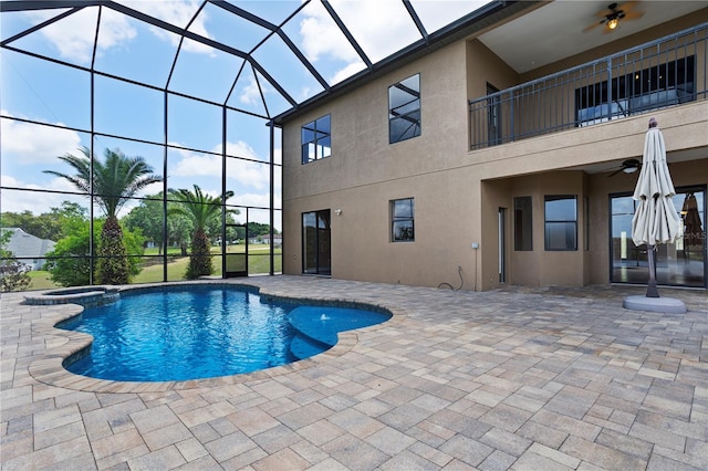 view of swimming pool featuring a patio, ceiling fan, a pool with connected hot tub, and a lanai