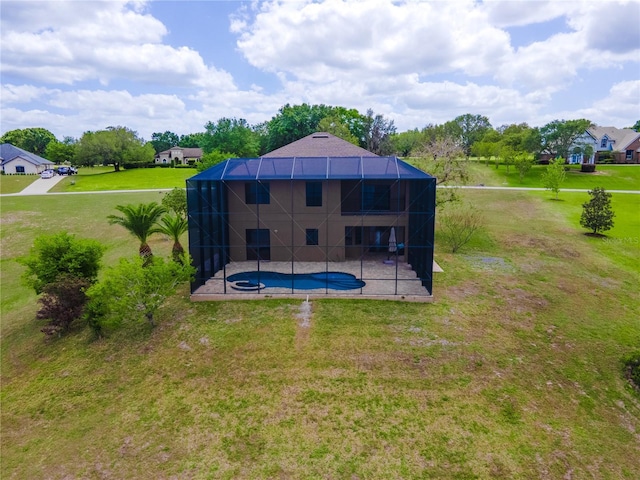 rear view of house featuring a lawn, a patio, an outdoor pool, and glass enclosure
