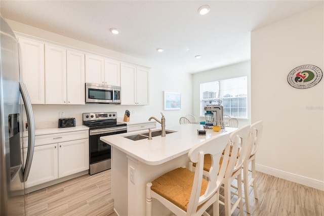 7968 Shaker St, Kissimmee, FL 34747 - kitchen featuring a sink, a kitchen breakfast bar, light wood-style floors, white cabinetry, and stainless steel appliances