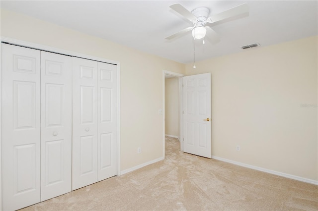 unfurnished bedroom featuring baseboards, a closet, light colored carpet, and visible vents