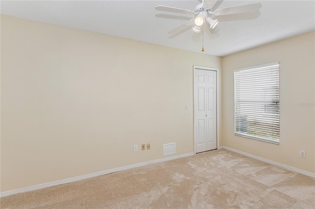 unfurnished room featuring visible vents, light carpet, baseboards, and ceiling fan