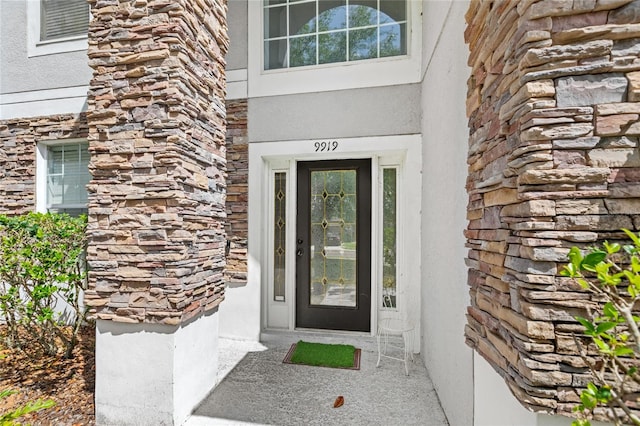 entrance to property featuring stucco siding and stone siding