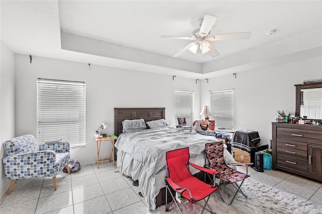 bedroom with light tile patterned floors, a ceiling fan, and a raised ceiling