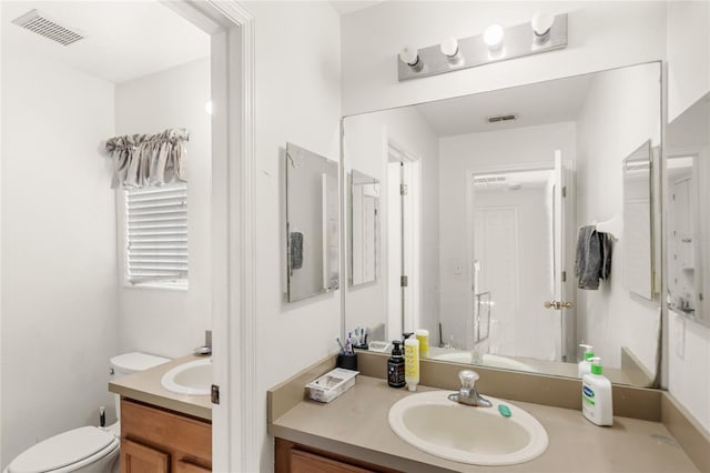 bathroom featuring toilet, vanity, and visible vents