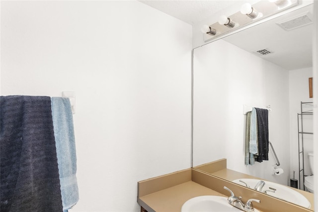 bathroom with toilet, vanity, and visible vents