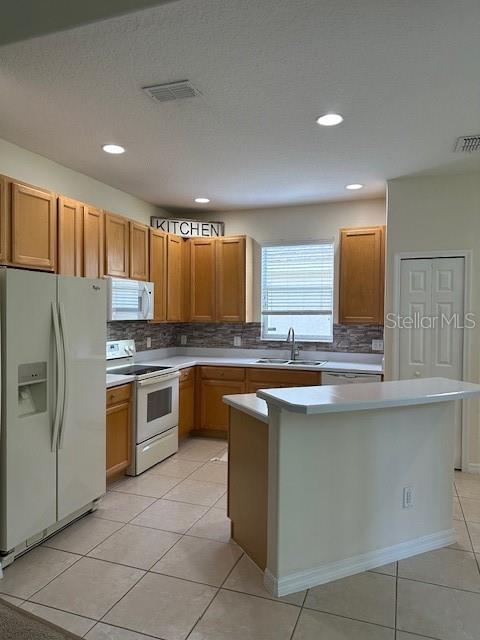 9723 Pecky Cypress Way, Orlando, FL 32836 - kitchen with white appliances, backsplash, light tile patterned floors, light countertops, and recessed lighting