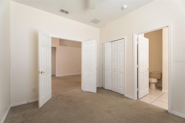 9723 Pecky Cypress Way, Orlando, FL 32836 - unfurnished bedroom with carpet flooring, a closet, ensuite bathroom, and tile patterned flooring