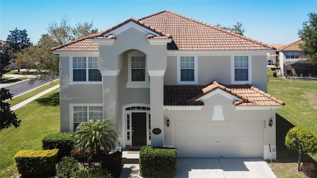 mediterranean / spanish-style house featuring a front lawn, concrete driveway, stucco siding, and a tile roof