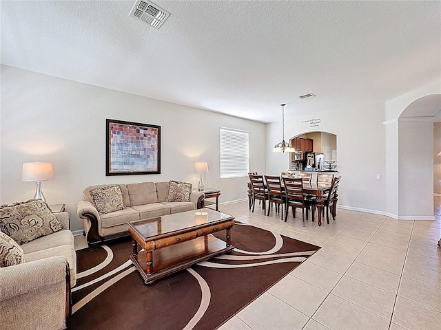 living area with visible vents, baseboards, arched walkways, and light tile patterned flooring