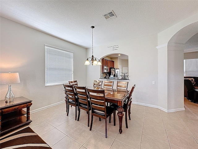 dining area with light tile patterned floors, baseboards, arched walkways, and visible vents