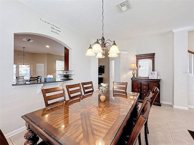 dining space featuring arched walkways, visible vents, a textured ceiling, and an inviting chandelier