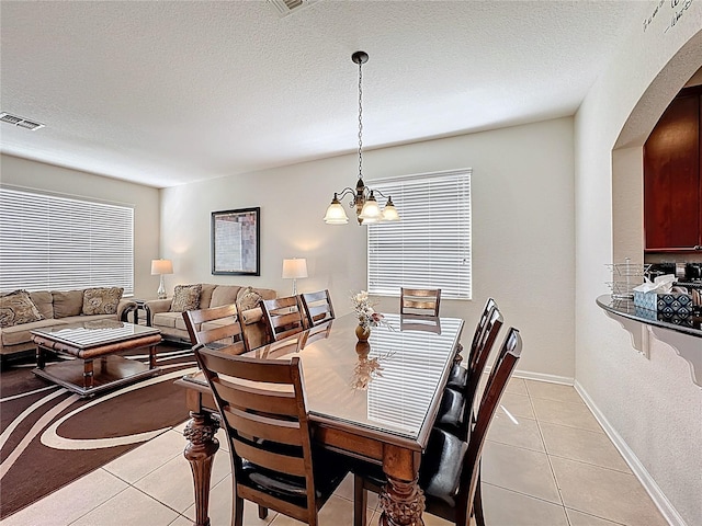 dining space featuring visible vents, baseboards, light tile patterned floors, arched walkways, and a chandelier