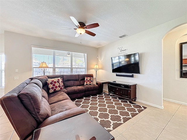 living room featuring arched walkways, light tile patterned floors, a ceiling fan, and visible vents