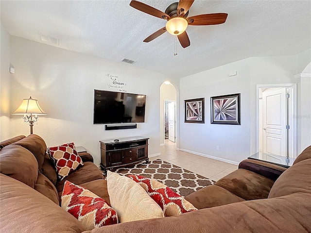 living room with light tile patterned floors, arched walkways, a textured ceiling, a ceiling fan, and visible vents