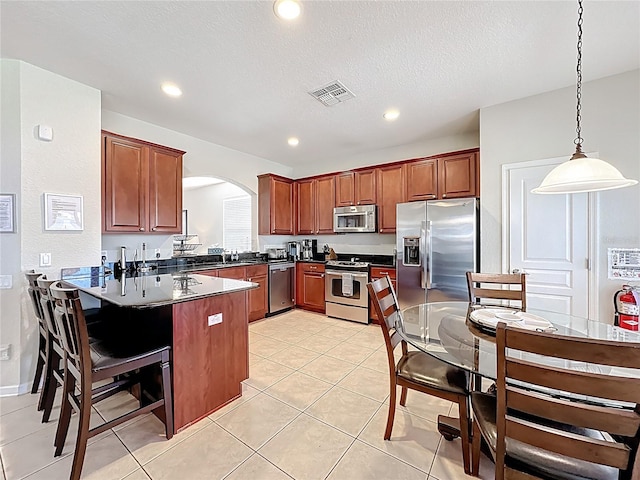 kitchen featuring a peninsula, arched walkways, visible vents, appliances with stainless steel finishes, and dark countertops