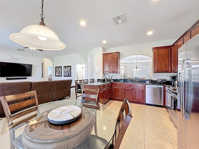 kitchen with visible vents, reddish brown cabinets, arched walkways, and stainless steel appliances