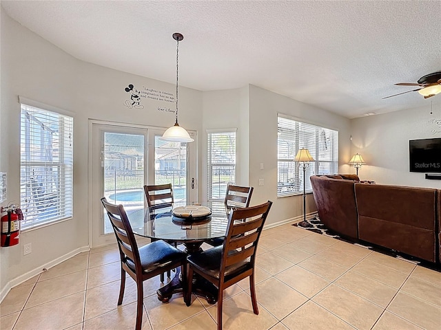 dining room featuring baseboards, a textured ceiling, a ceiling fan, and light tile patterned flooring