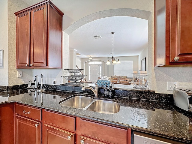 kitchen featuring dark stone countertops, visible vents, arched walkways, a sink, and a textured wall