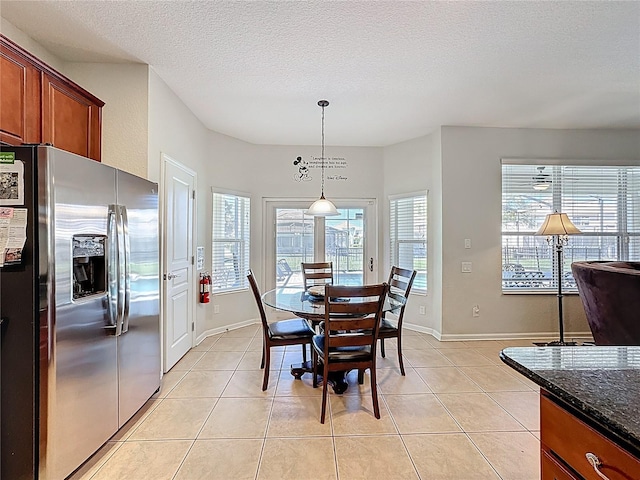 dining area featuring a textured ceiling, light tile patterned flooring, and baseboards