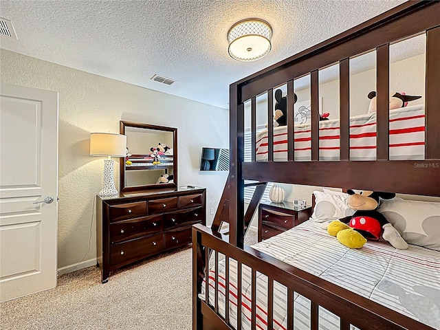 carpeted bedroom with a textured wall, visible vents, and a textured ceiling