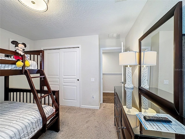 bedroom featuring a closet, baseboards, visible vents, a textured ceiling, and carpet floors